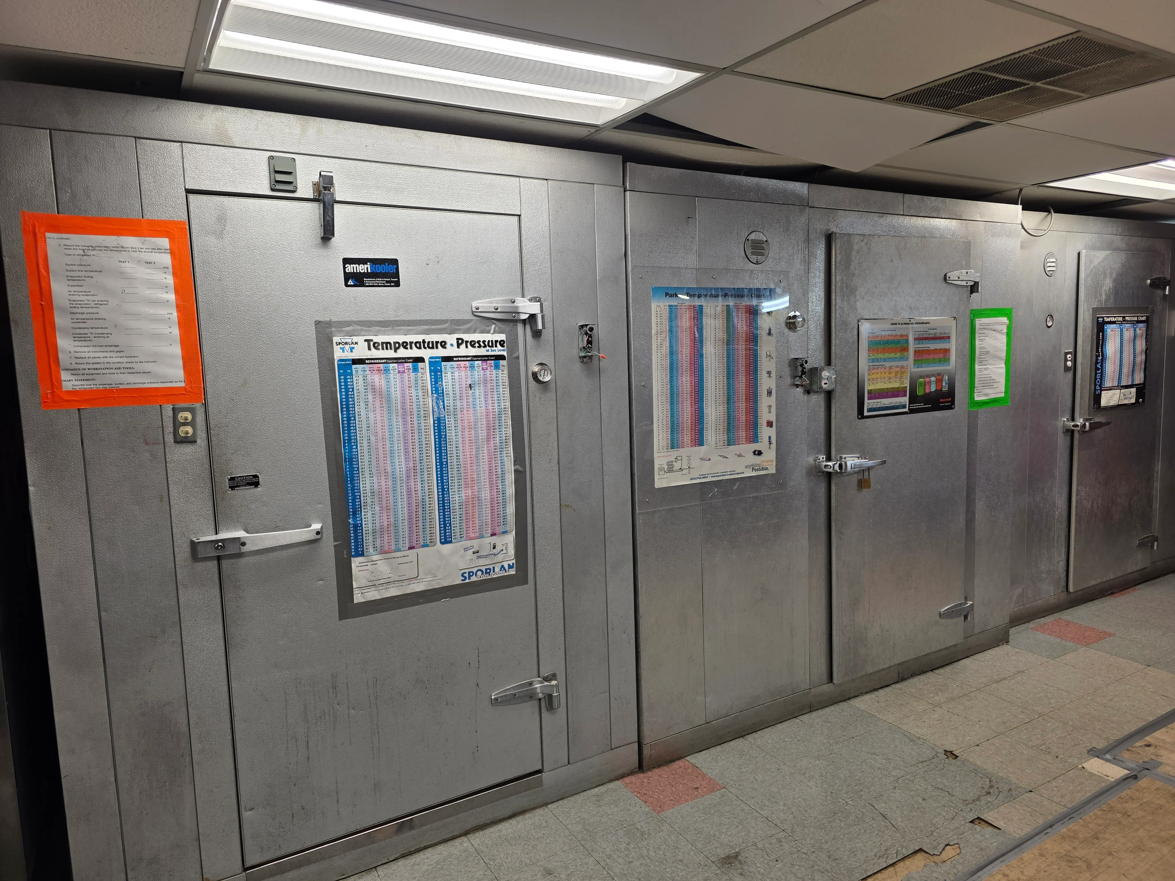 Multiple stainless steel commercial walk-in coolers with temperature-pressure charts and control documentation