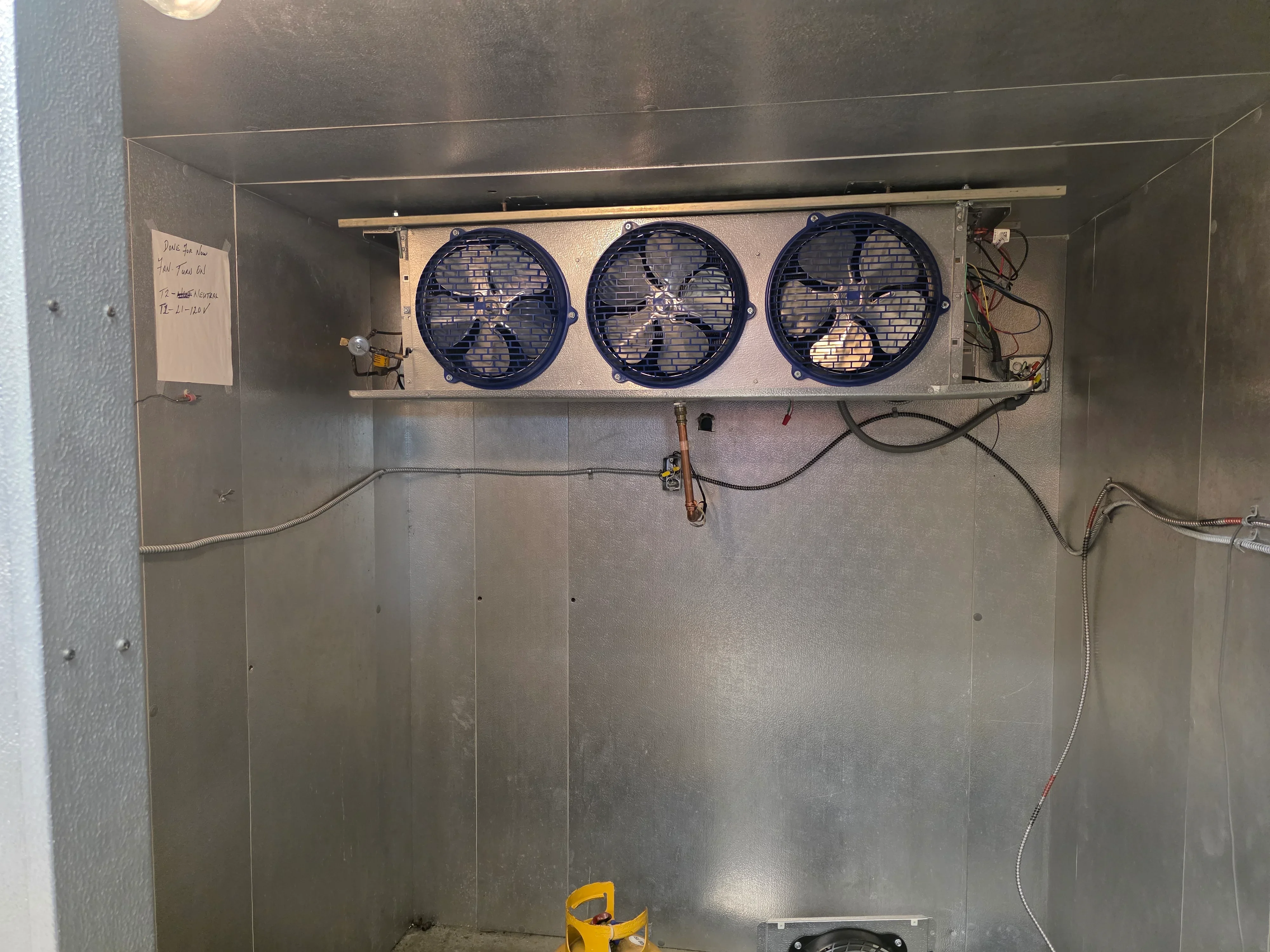Three-fan evaporator coil unit installed in stainless steel refrigeration enclosure with piping