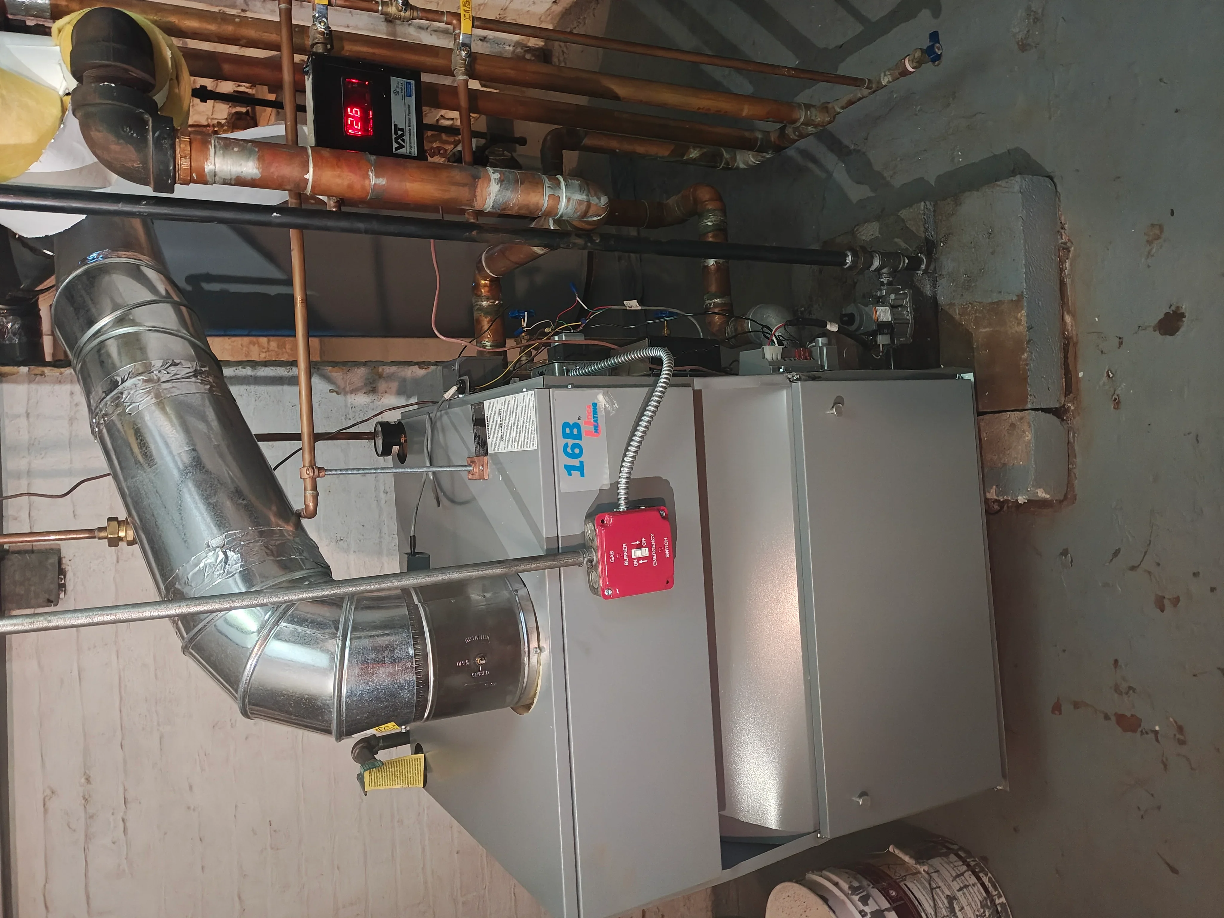 Commercial boiler system with copper piping, ductwork, and digital controls installed in basement