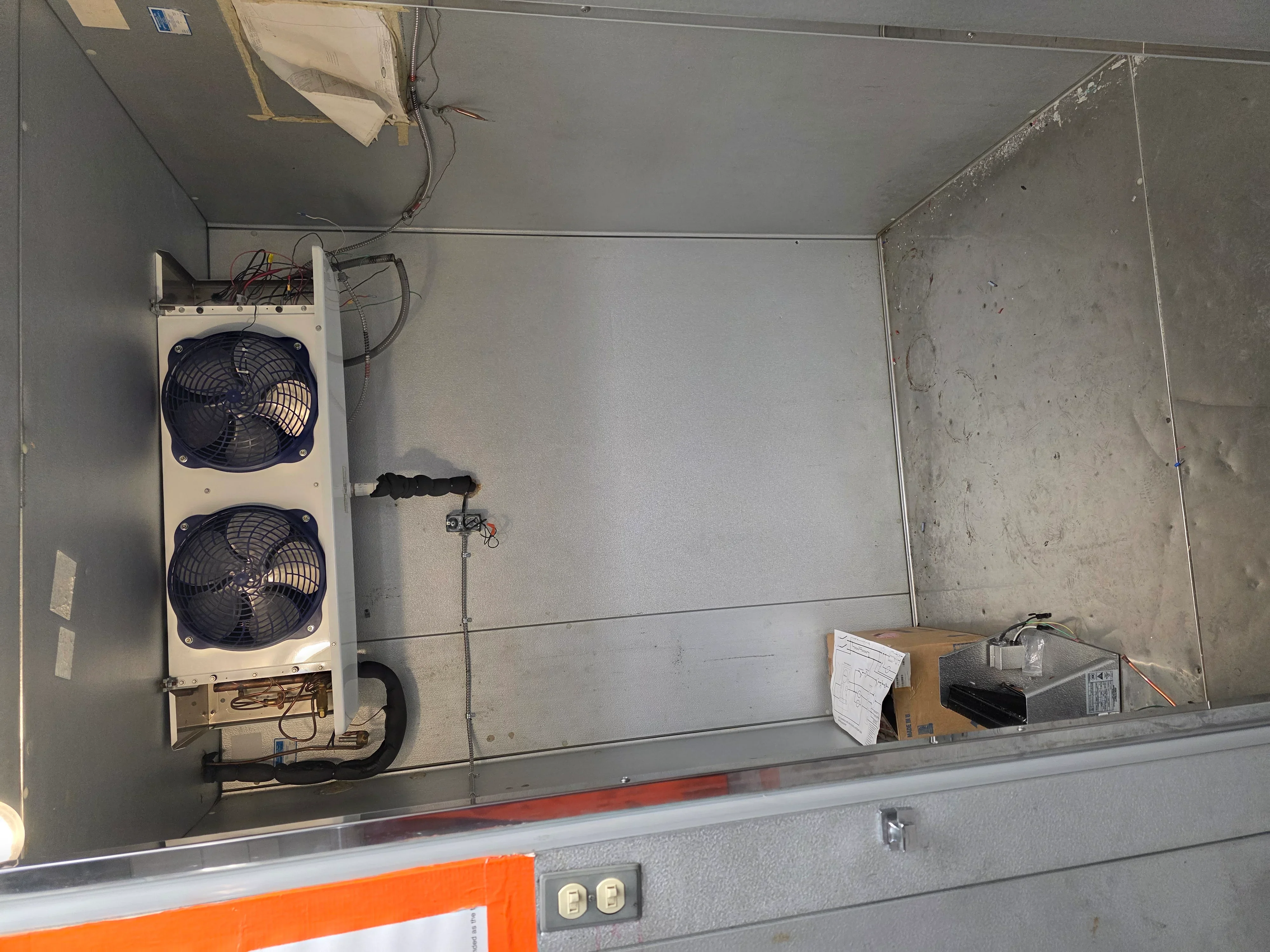 Dual-fan commercial HVAC condensing unit mounted on exterior wall with electrical connections
